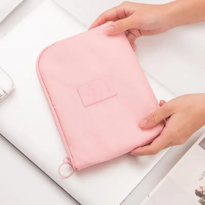 Travel Storage Bag for Digital Products and Cables in pink, held by hands with a minimalistic background.