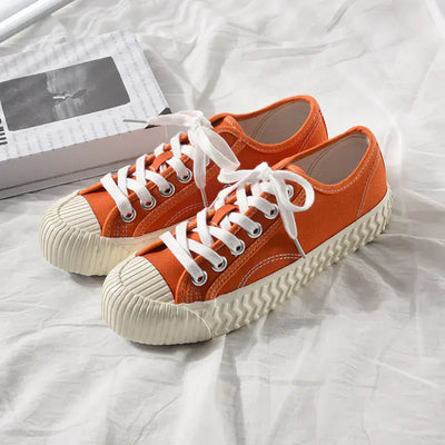mens-and-womens-canvas-sneakers in orange with white laces on a light background.