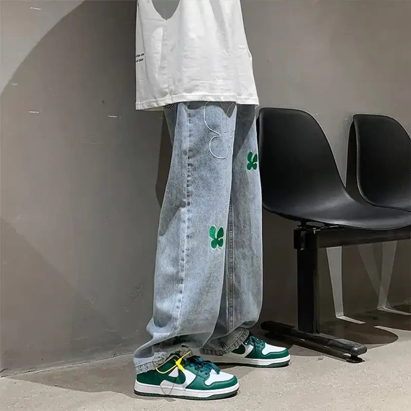 Embroidered High Street Jeans for Men featuring bold green embroidery, styled with urban sneakers, showcasing streetwear fashion.