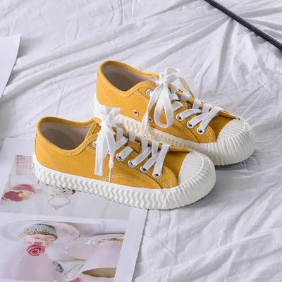 Mens and womens canvas sneakers in bright yellow color with white laces on a stylish background.