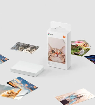 Xiaomi Mini Bluetooth Photo Printer with Zink photo paper and printed photos scattered around.