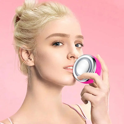 Woman using Electric Silicone Pore Cleaner and Heating Facial Wash against a pink background for skincare routine.