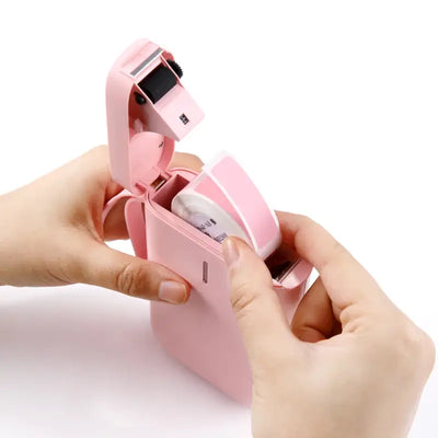 Hands loading a label roll into a pink Bluetooth Label Printer for fast and compact labeling.