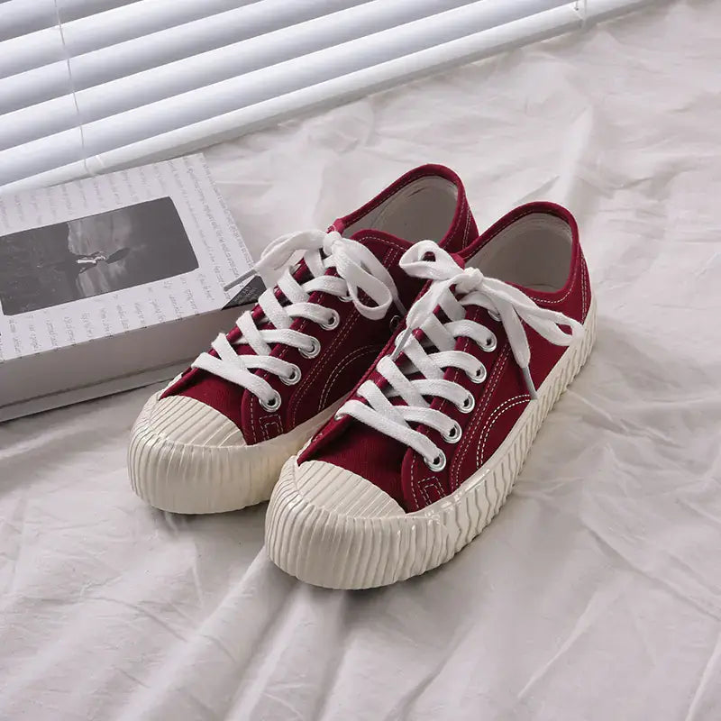 mens-and-womens-canvas-sneakers in red color with white laces on a light background.