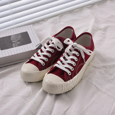 mens-and-womens-canvas-sneakers in red color with white laces on a light background.