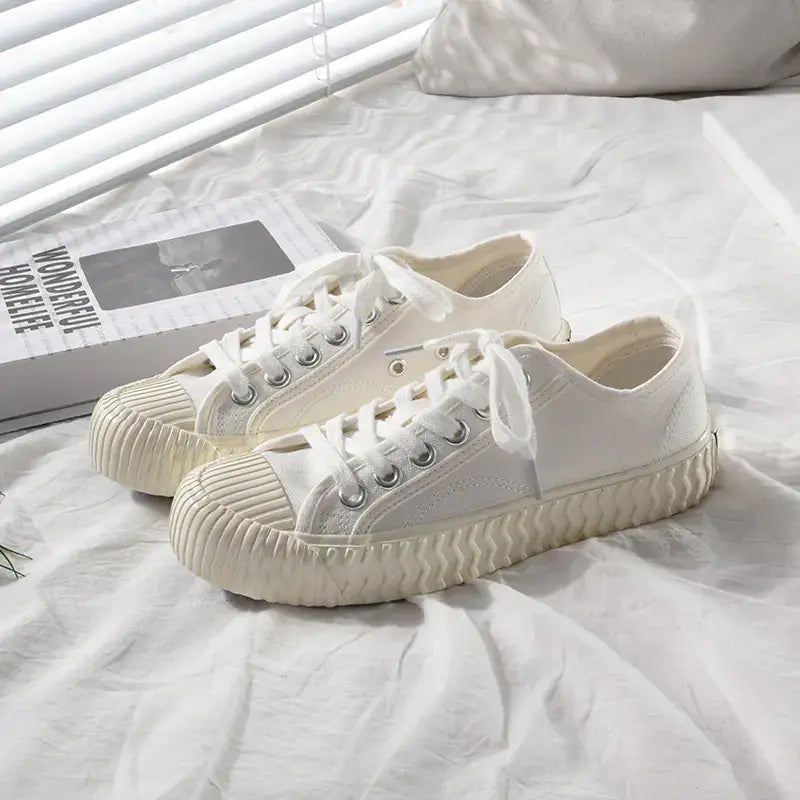 mens-and-womens-canvas-sneakers in white color displayed on a bed with soft lighting.