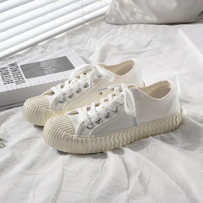 mens-and-womens-canvas-sneakers in white color displayed on a bed with soft lighting.