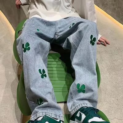 Embroidered High Street Jeans for Men featuring green embroidered clovers, styled casually with sneakers.