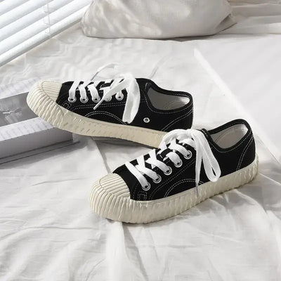 mens-and-womens-canvas-sneakers in black with white laces on a bed with soft lighting